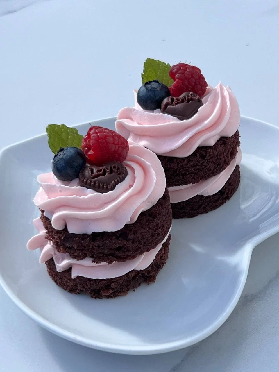 Chocolate cupcakes decorated with pink cream and fresh berries